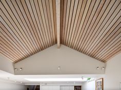 the interior of a modern house with wood slats on the ceiling and white walls