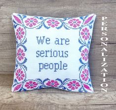 a cross stitch pillow with the words, we are serious people on it and flowers