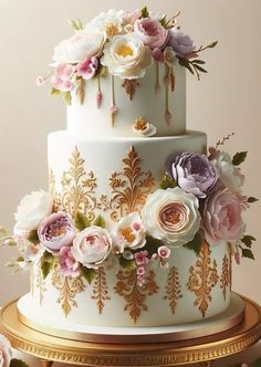 a three tiered wedding cake with flowers on the top and gold trimmings