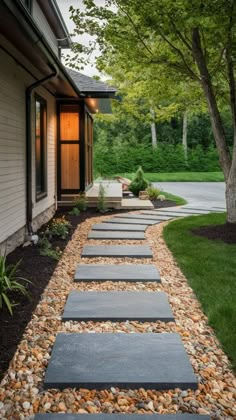 a walkway made out of stones leads to a house with trees in the front yard