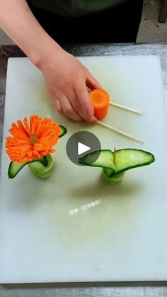 the person is cutting up vegetables with chopsticks and an orange flower on top