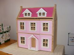 a pink doll house sitting on top of a green table next to a teddy bear