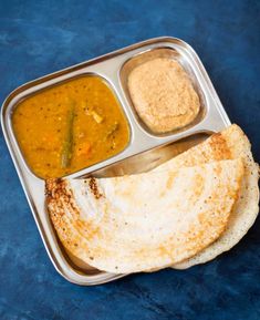 a metal tray filled with food on top of a blue table