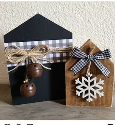 two wooden houses decorated with christmas ornaments and twine bows, tied to each other