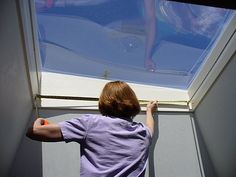 a young boy standing in front of a window looking up at something on the ground