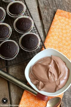 chocolate cupcakes with frosting in a white bowl next to an orange napkin