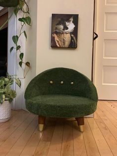 a green chair sitting on top of a hard wood floor next to a potted plant