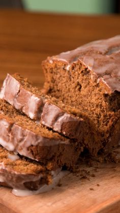 sliced loaf of chocolate banana bread with icing on wooden cutting board next to knife