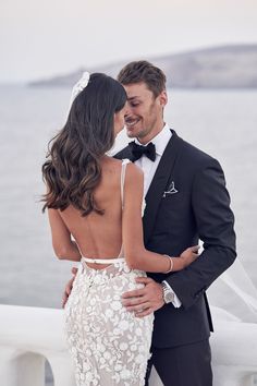 a bride and groom embracing each other in front of the water at their wedding ceremony