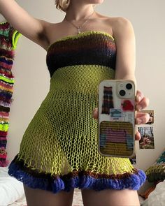 a woman is holding up her cell phone and wearing a dress made out of knitted material