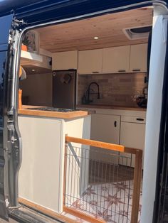 an open van door showing the kitchen and living room inside it, as seen from outside