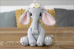 a crocheted elephant sitting on top of a wooden table