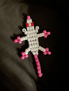 the beaded toy is shaped like a person with red eyes and legs, on a black surface