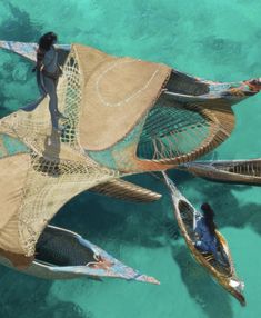 two people in canoes floating on clear blue water with nets attached to the sides