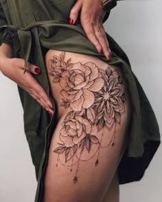 a woman is showing off her thigh with flowers on the side and tattoos on it