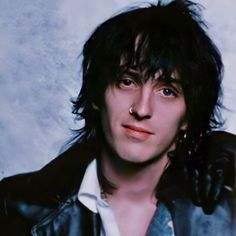 a man with black hair wearing a leather jacket