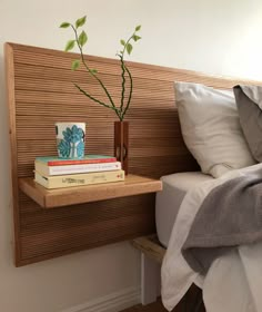 a bed with two books and a plant on the headboard next to each other