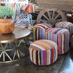 several colorful striped chairs and stools in a room with an old wagon behind them