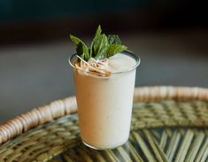 a glass filled with some kind of drink on top of a wicker tablecloth