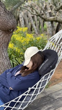 a woman sitting in a hammock with her head resting on her hands and feet