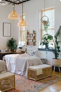 a bedroom with two beds and plants in the window sill, hanging lights above them