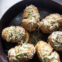 baked potatoes with parmesan cheese and herbs in a frying pan on a table