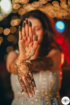 a woman is holding her hands up to show off her hendi