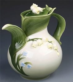 a white and green vase with flowers on it