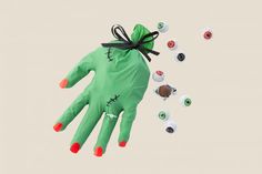 a green hand with red nails and black bow on it is flying through the air