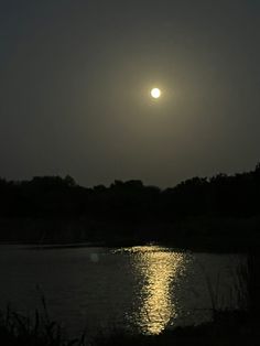 the sun is shining brightly in the night sky over a body of water and trees