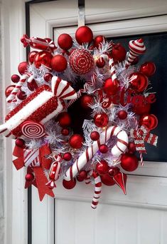 a wreath with candy canes and candies hanging on the front door for christmas