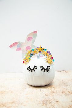 a white pumpkin with a crown on it's head sitting on top of a wooden table