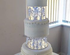 a three tiered wedding cake sitting on top of a table next to a window