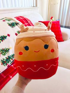 a person holding up a stuffed toy in the shape of a christmas pudding on a bed