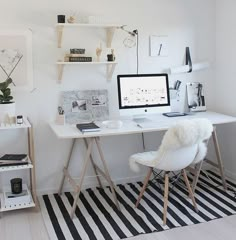 a white desk with a computer on top of it next to a black and white rug