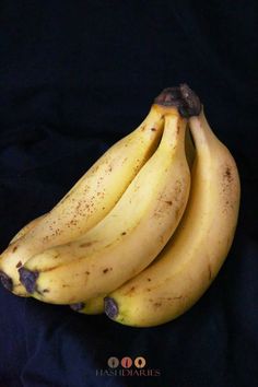 three bananas with brown spots on them sitting next to each other in front of a black background