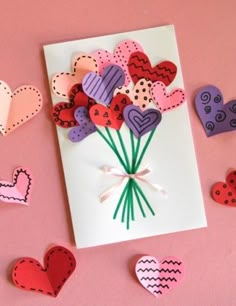 valentine's day card with paper hearts and flowers on pink background next to scissors