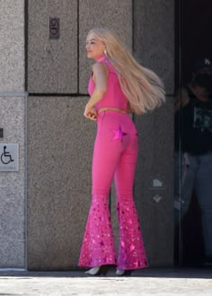 a woman with long blonde hair wearing pink pants