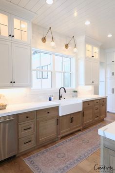 a large kitchen with white cabinets and wood flooring, along with a rug on the floor