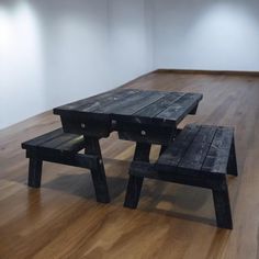 two wooden benches sitting on top of a hard wood floor next to a white wall