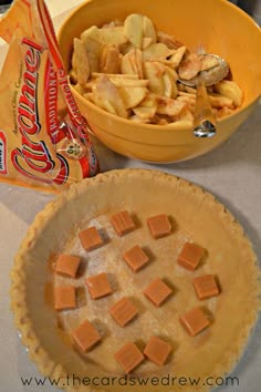 two pie pans filled with food next to a bowl of chips and a bag of candy