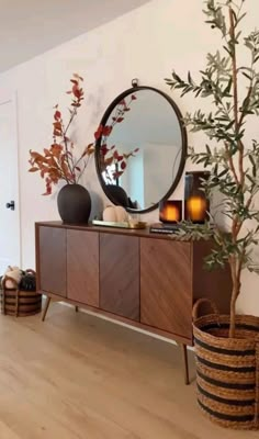 a living room with a large mirror on the wall next to a wooden cabinet and potted plant