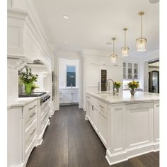 a large kitchen with white cabinets and wood floors