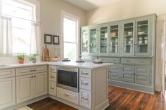 a kitchen with white cabinets and wood floors