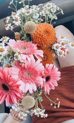 a woman is holding a bouquet of flowers in her hand while sitting in the back seat of a car