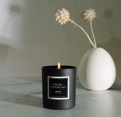 a black candle sitting next to a white vase