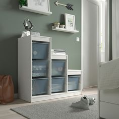 a room with green walls, white furniture and baskets on the floor in front of it