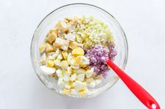 a bowl filled with diced up vegetables next to a red spoon