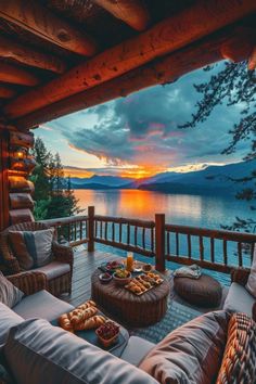 an outdoor deck with wicker furniture overlooking the lake at sunset or sunrise, in front of a log cabin