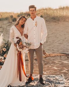 a man and woman are standing on the beach with flowers in their hair, dressed in white